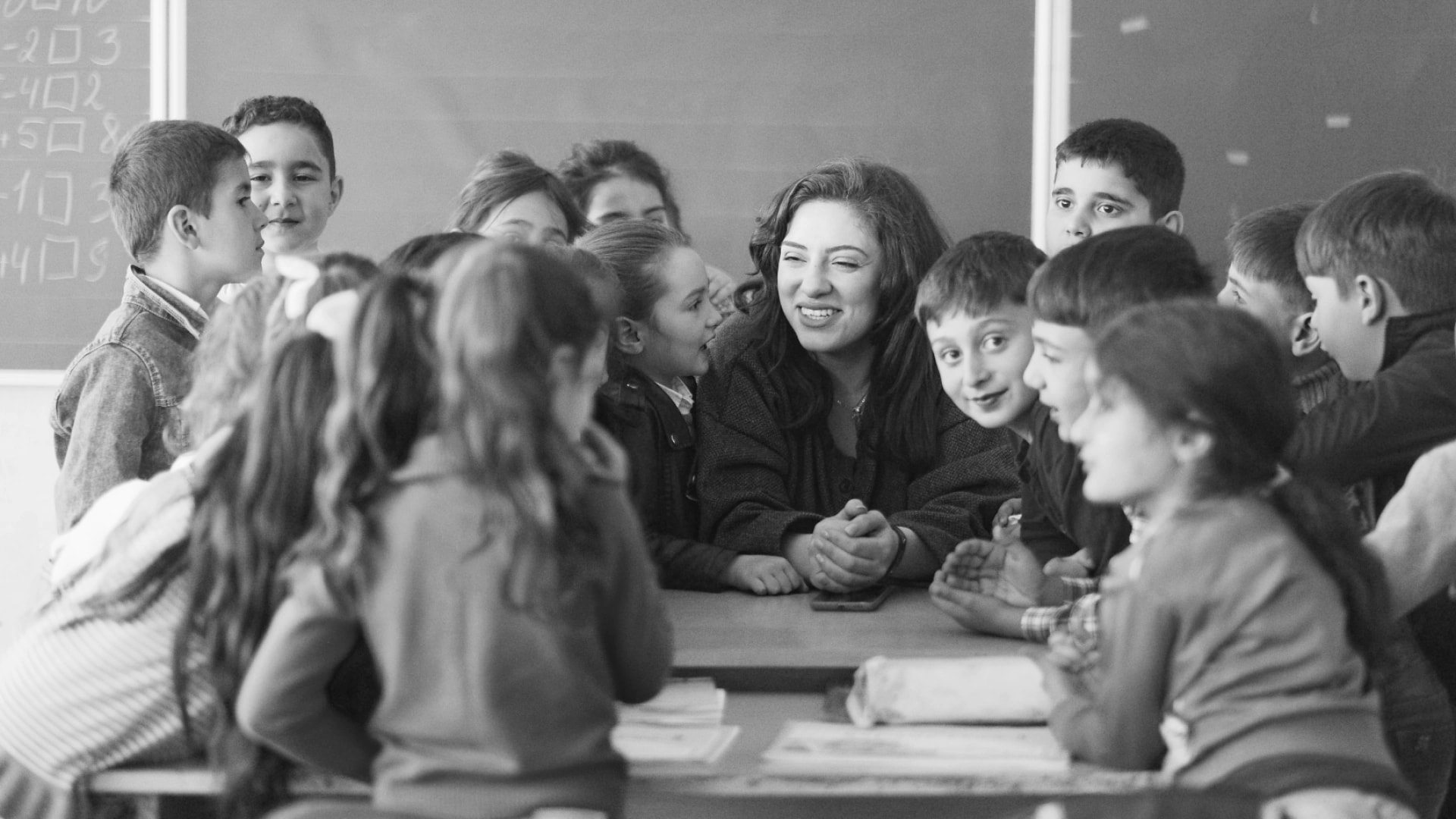 Armenian schoolchildren gathered in a circle around letter cards, seen from above